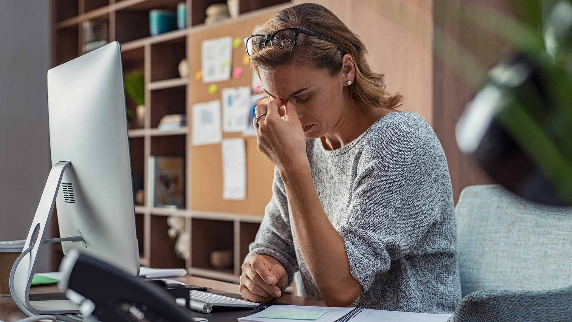 A stressed NDIS Provider sits at computer with head in hands as she prepares for Audit