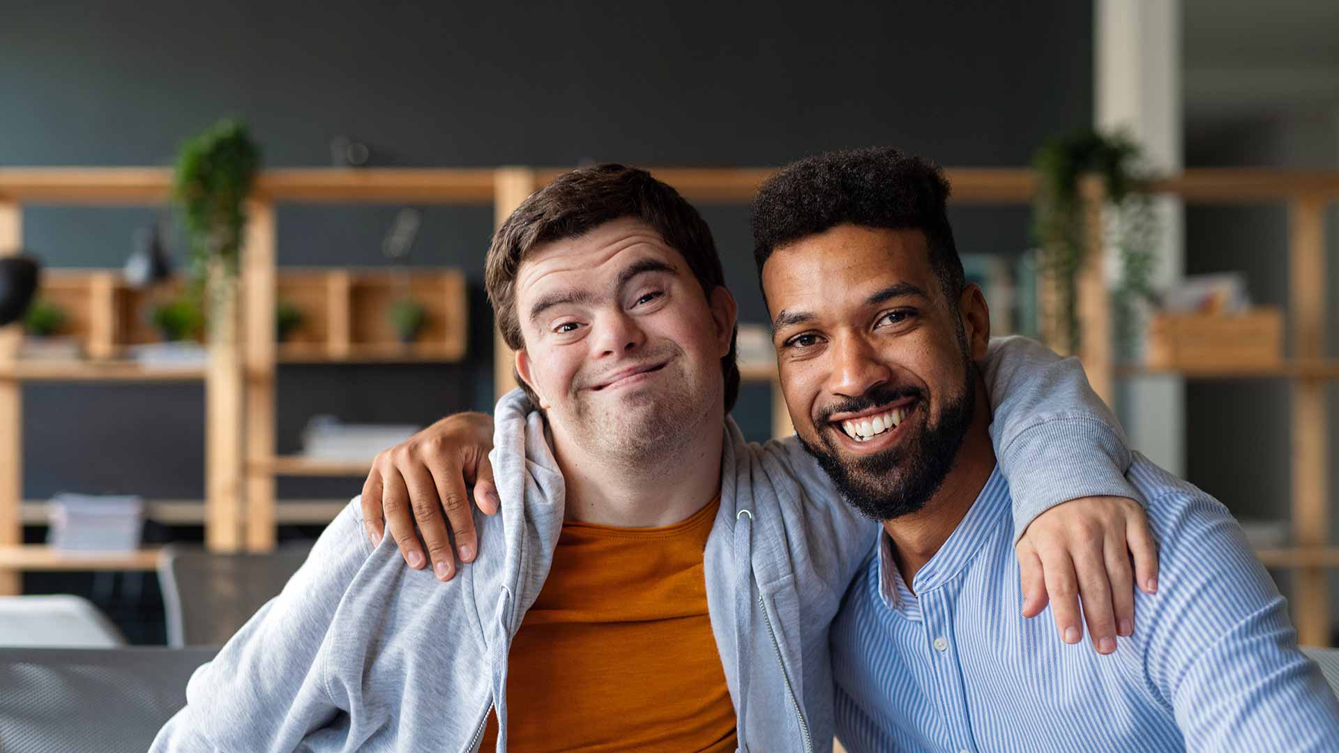Unregistered NDIS Providers: A man with downs syndrome and a support worker smile at the camera with arms around each other